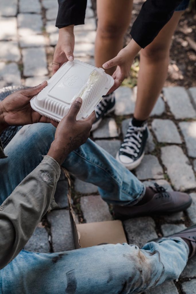 a-person-handing-out-food-to-a-person-in-shabby-clothes-9532267 A Person Handing Out Food to a Person in Shabby Clothes