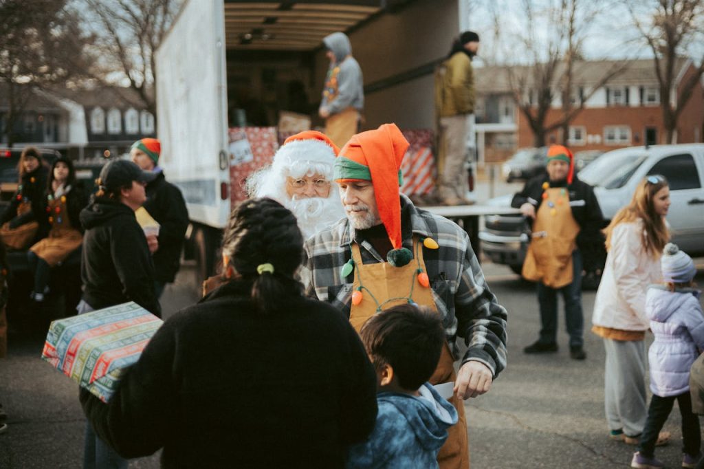 people-in-christmas-costumes-giving-away-presents-on-the-city-street-14831642 Santa and volunteers distribute gifts from a truck in a community Christmas event.